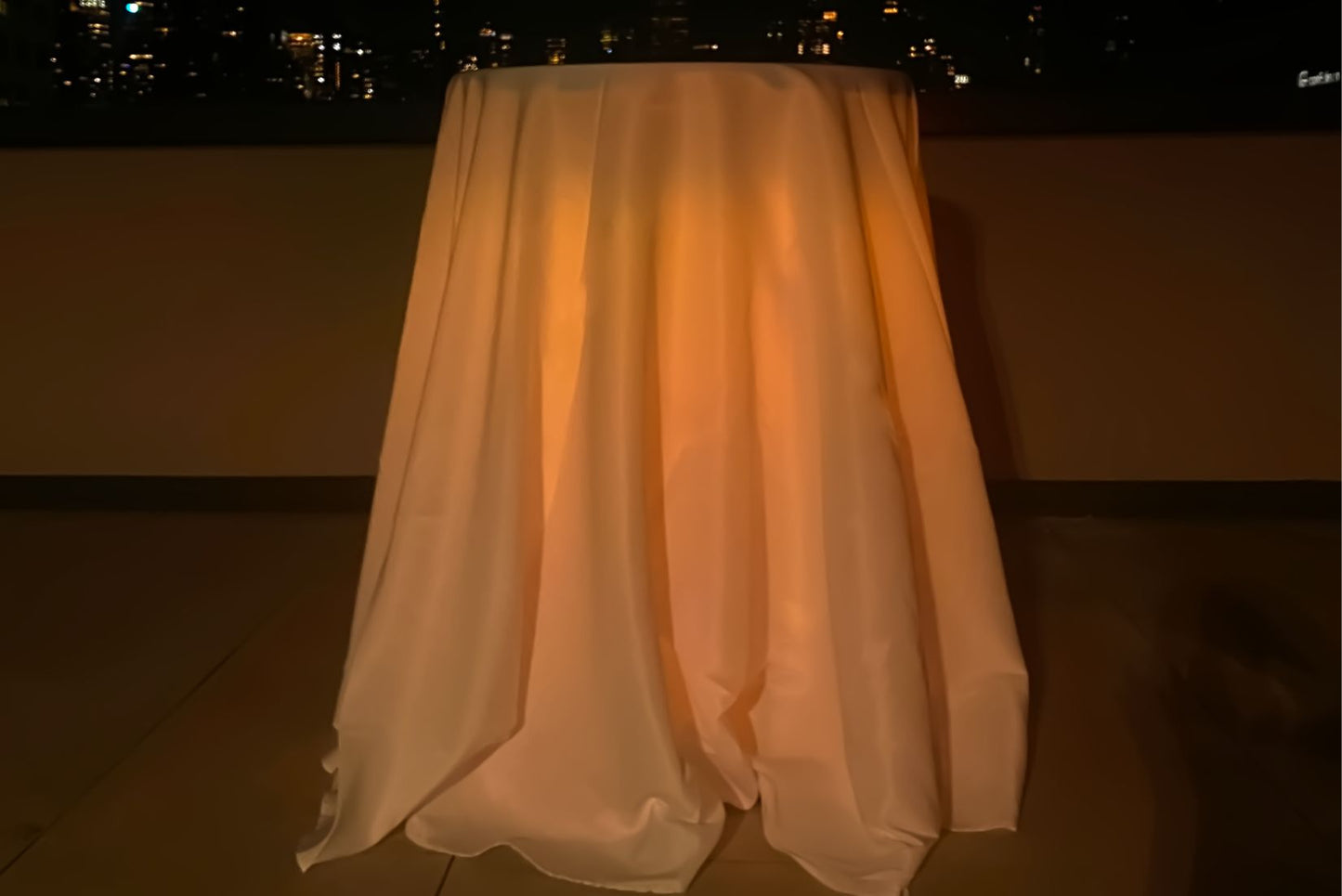 Highboy pub table with draped cloth and amber lighting. Table is for rent in Queens  New York